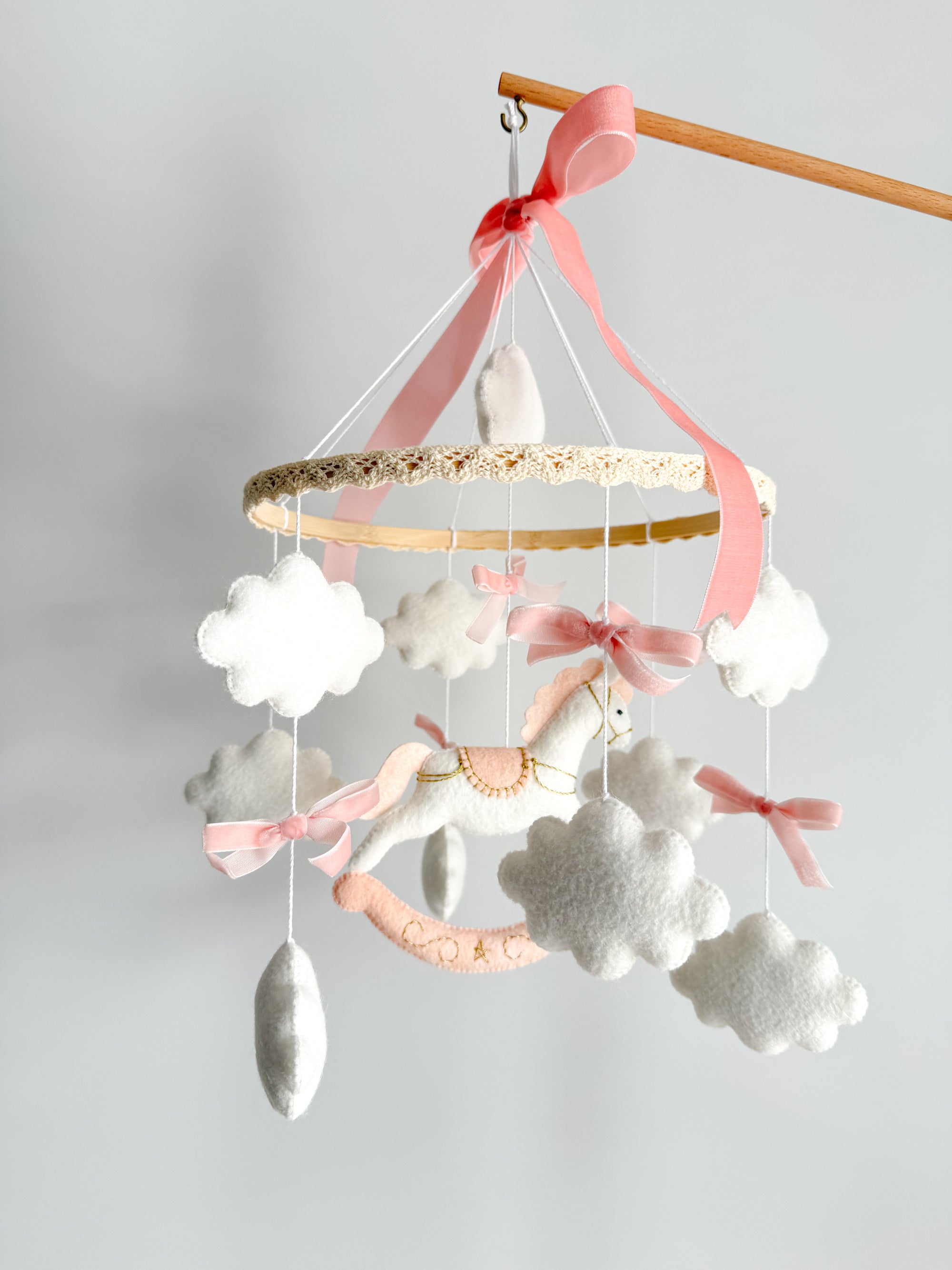 Mobile with a white rocking horse and a pink bow