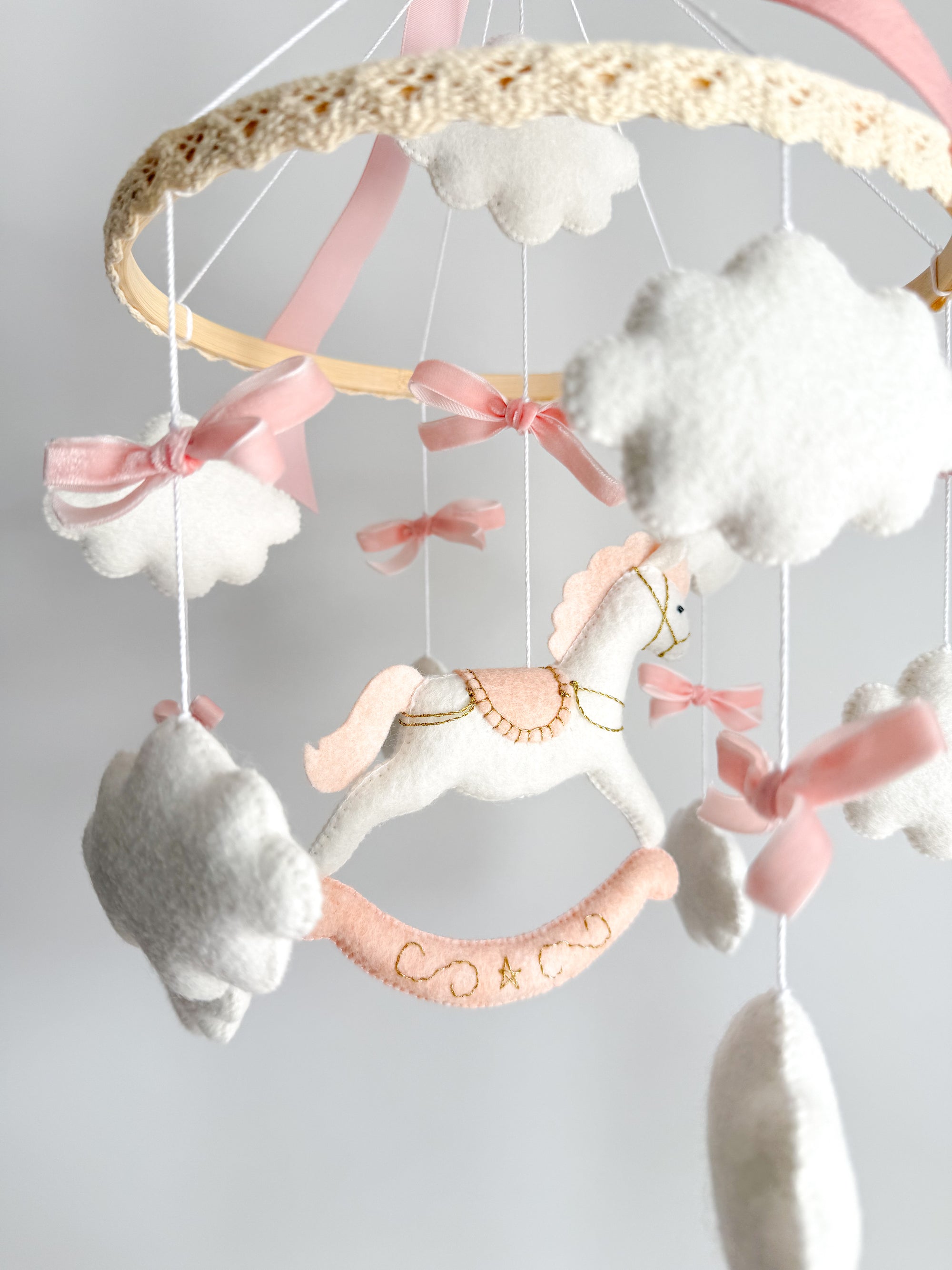 Mobile with a white rocking horse and a pink bow