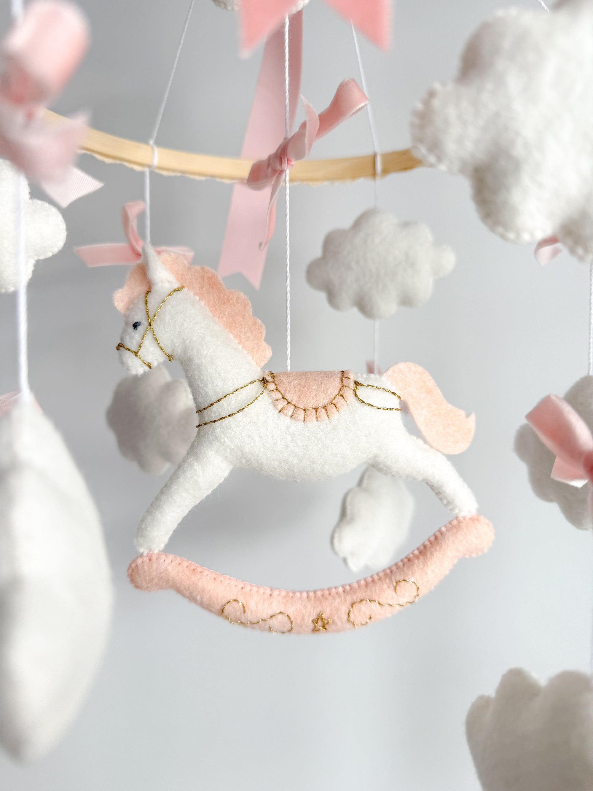 Mobile with a white rocking horse and a pink bow