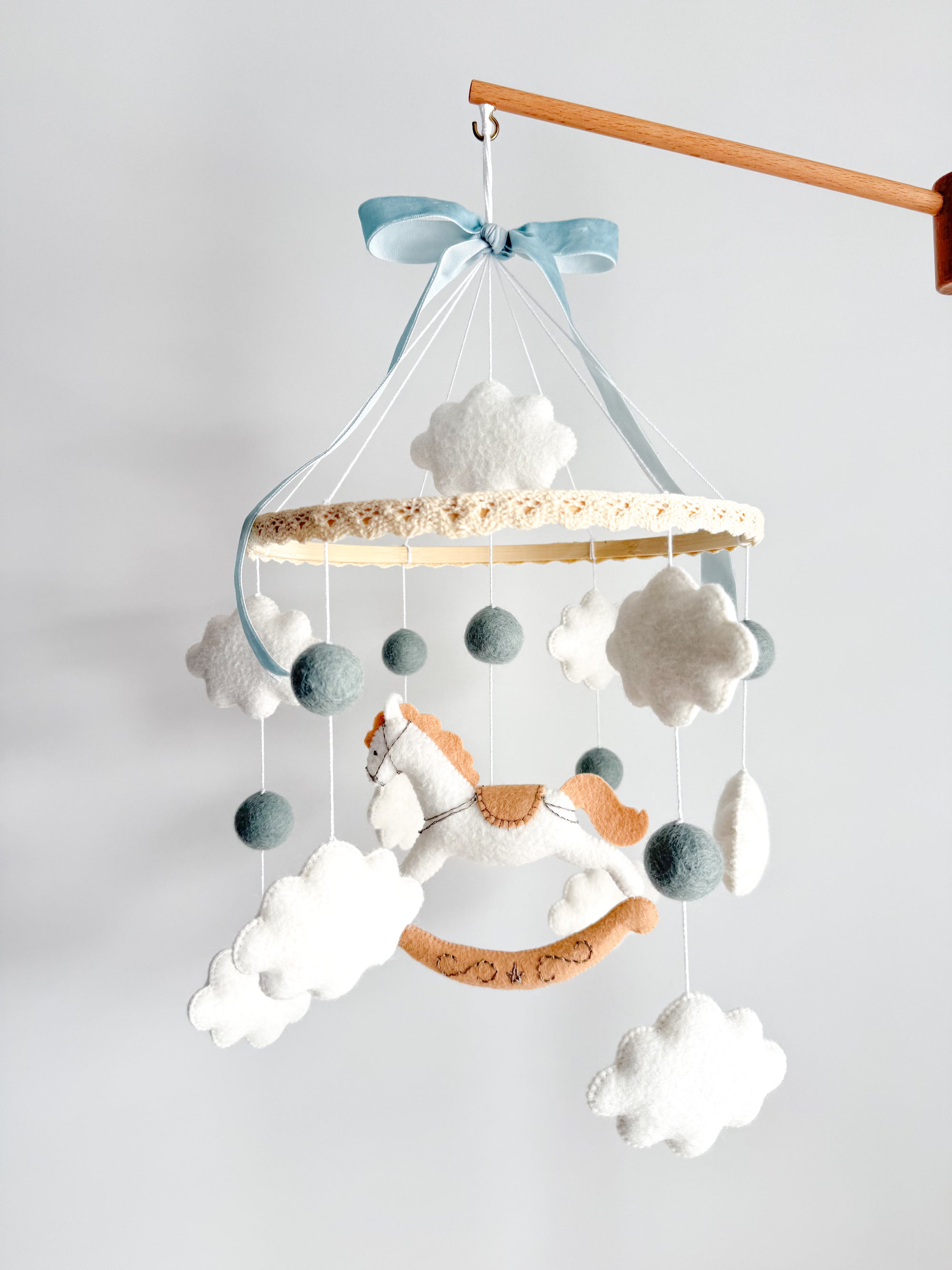 Mobile with a white rocking horse and a blue bow