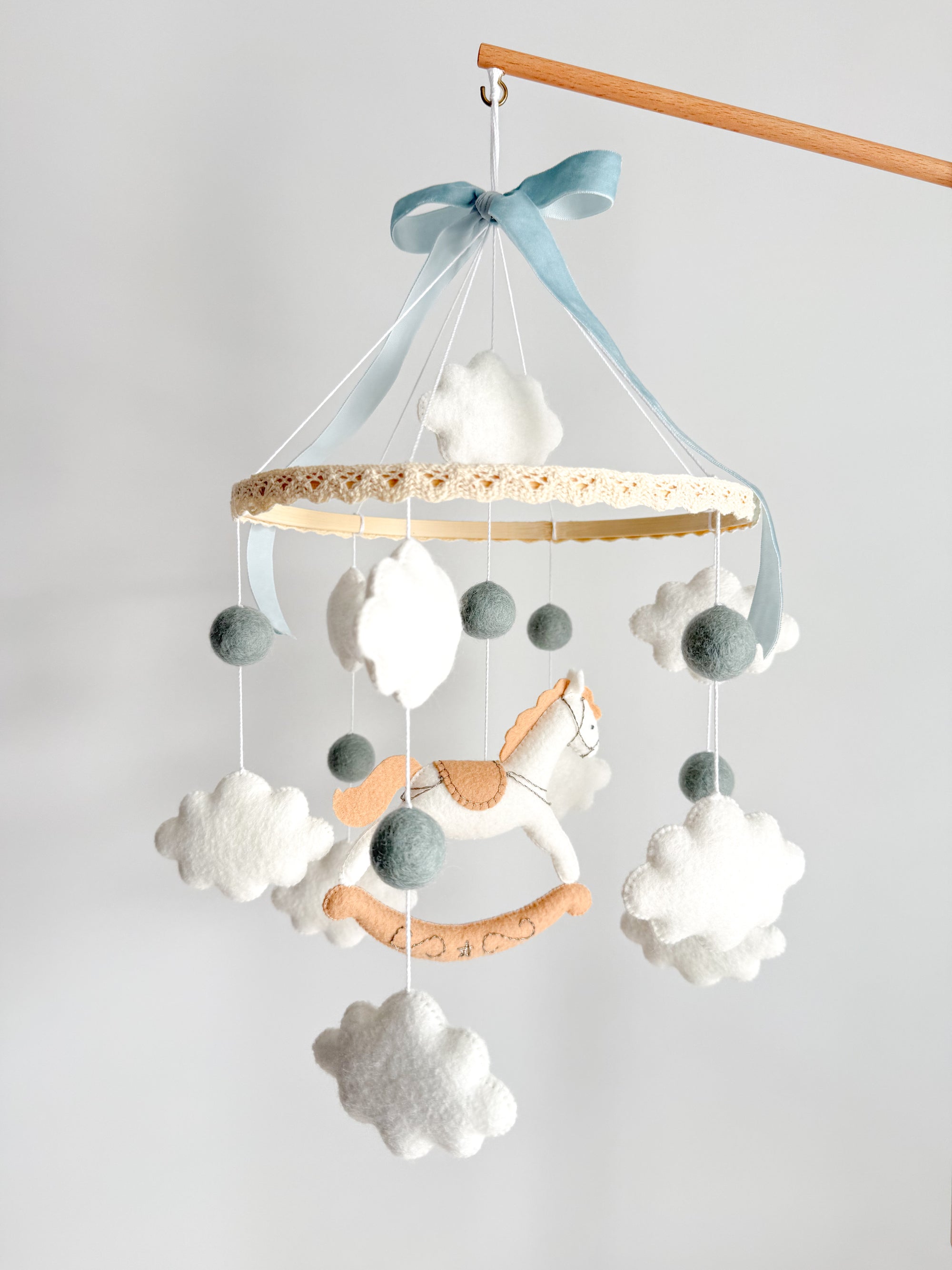 Mobile with a white rocking horse and a blue bow