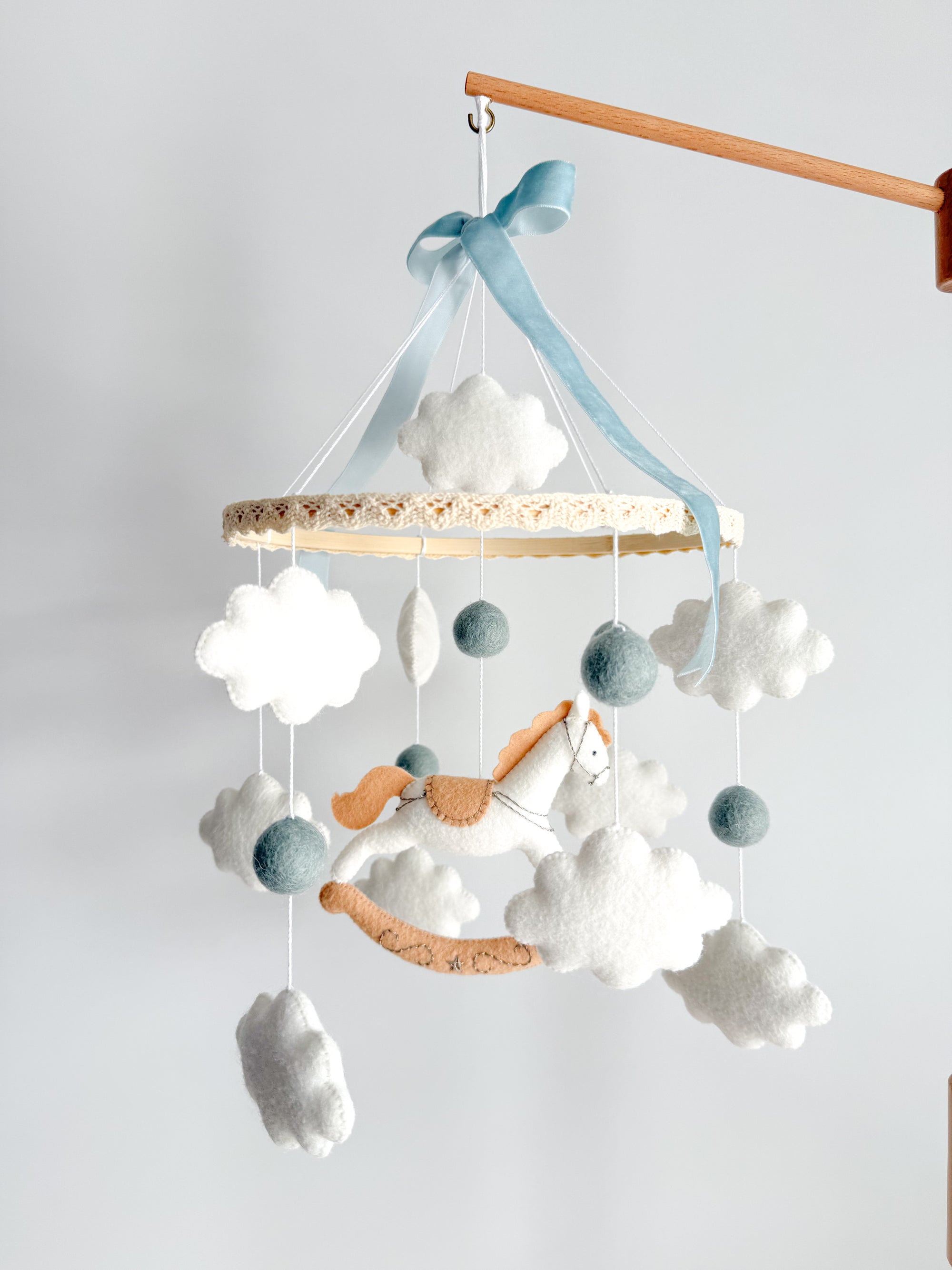 Mobile with a white rocking horse and a blue bow