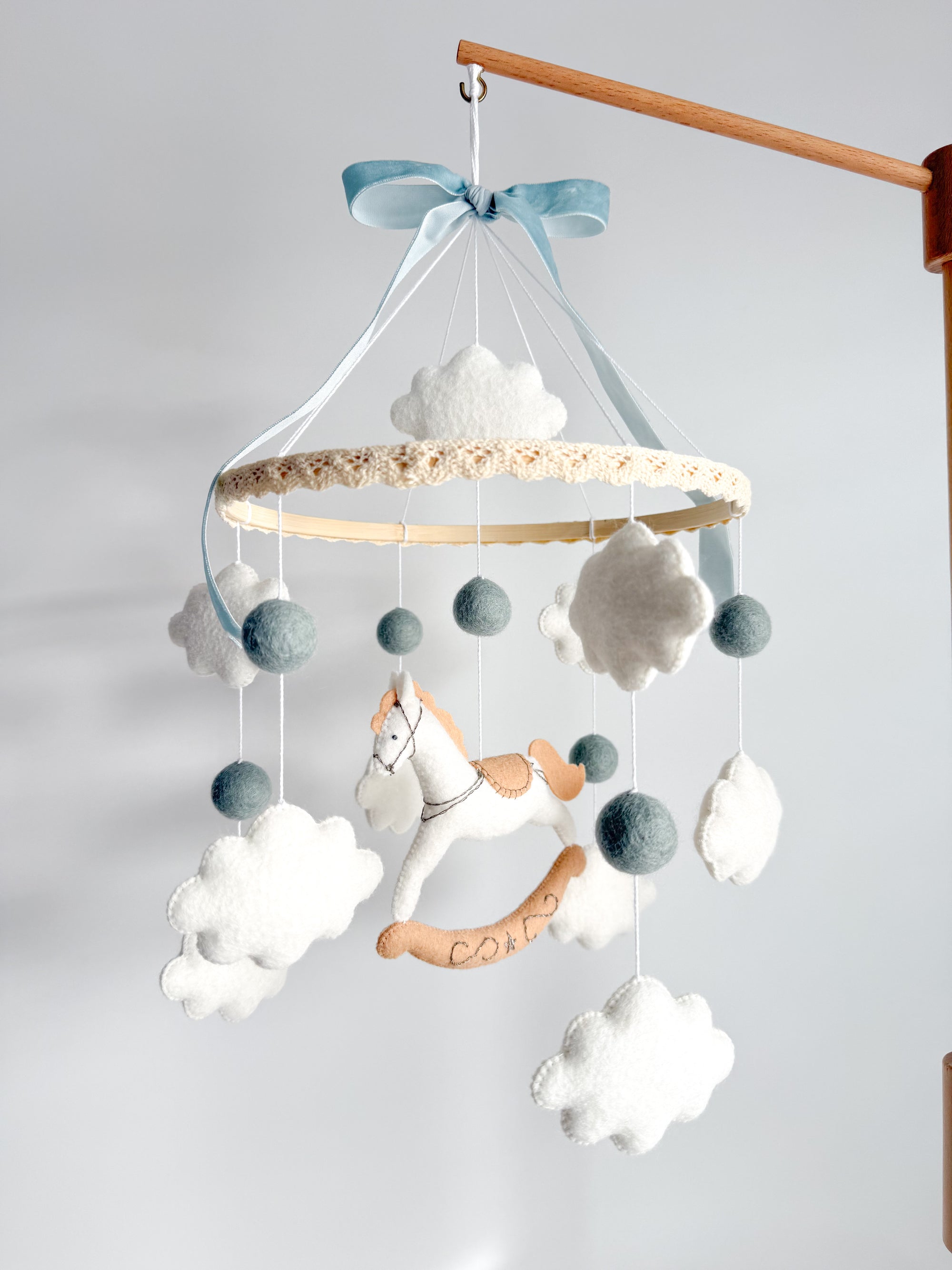 Mobile with a white rocking horse and a blue bow