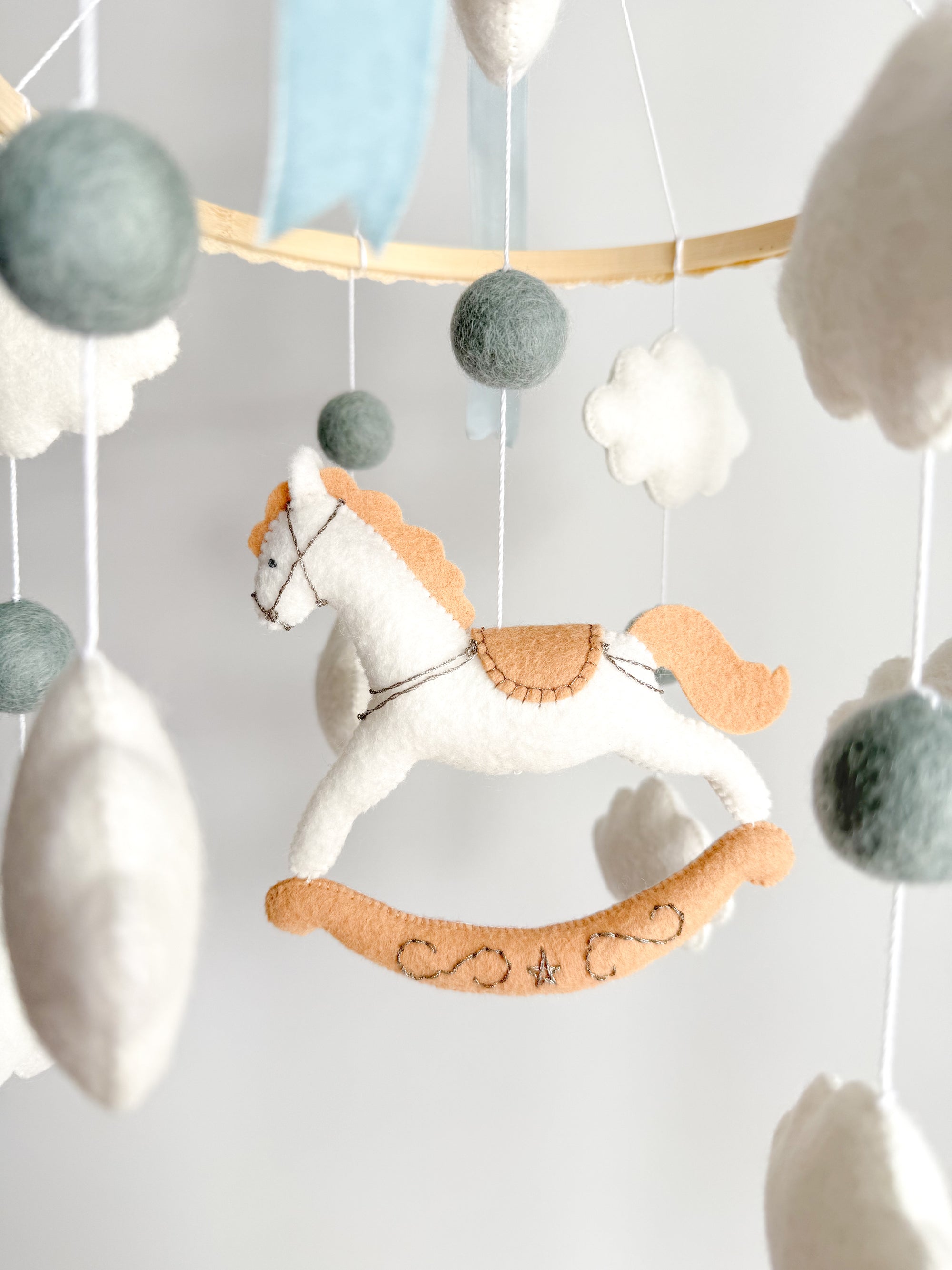Mobile with a white rocking horse and a blue bow