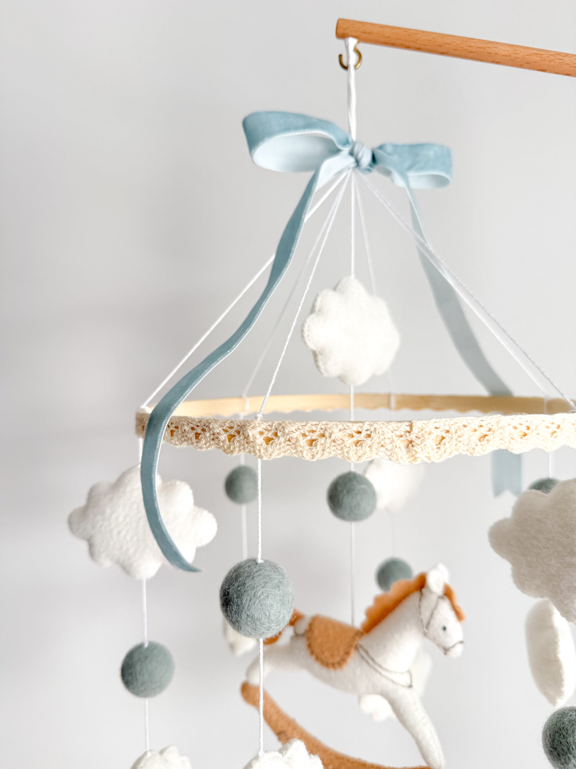 Mobile with a white rocking horse and a blue bow